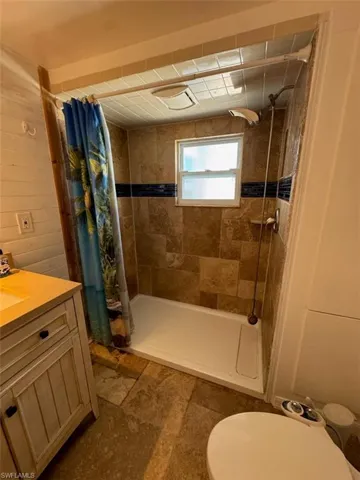 Bathroom featuring a shower stall, vanity, and stone finish flooring