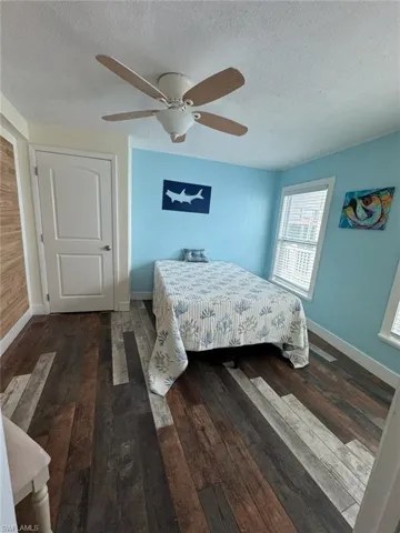 Bedroom with a textured ceiling, hardwood / wood-style flooring, and a ceiling fan