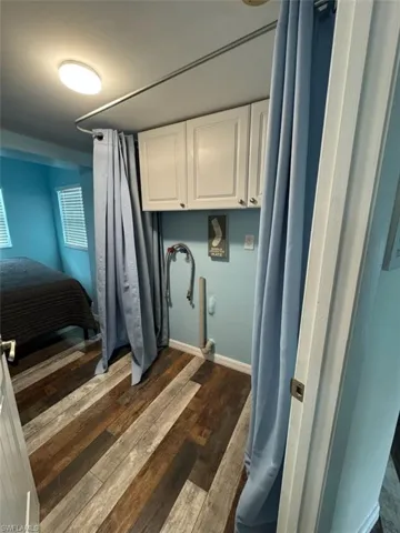 Laundry area featuring cabinet space and dark wood-style floors