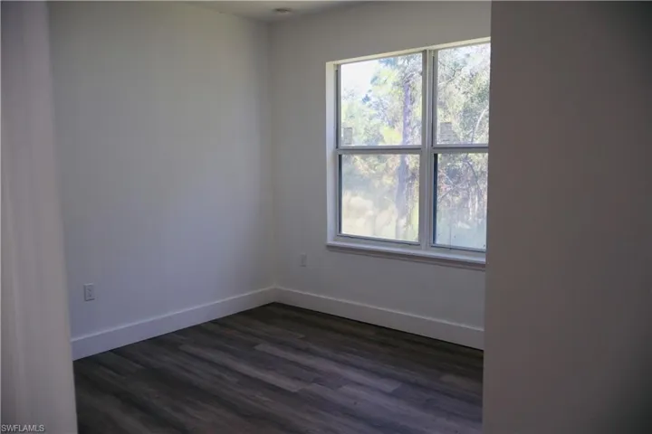 Empty room with dark wood-style flooring and baseboards