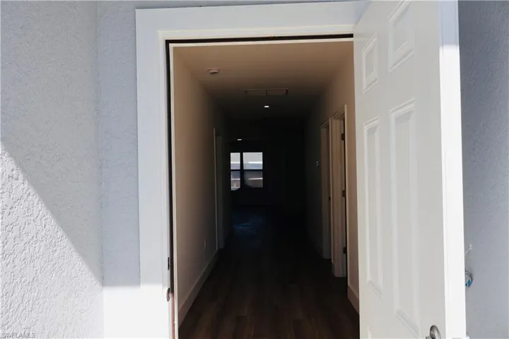 Corridor featuring dark wood-style floors and a textured wall