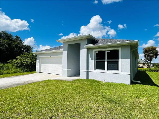 View of front facade featuring driveway, a front yard, an attached garage, and stucco siding