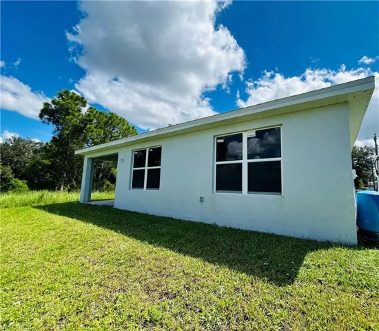 View of side of property featuring stucco siding, a yard, and a patio area