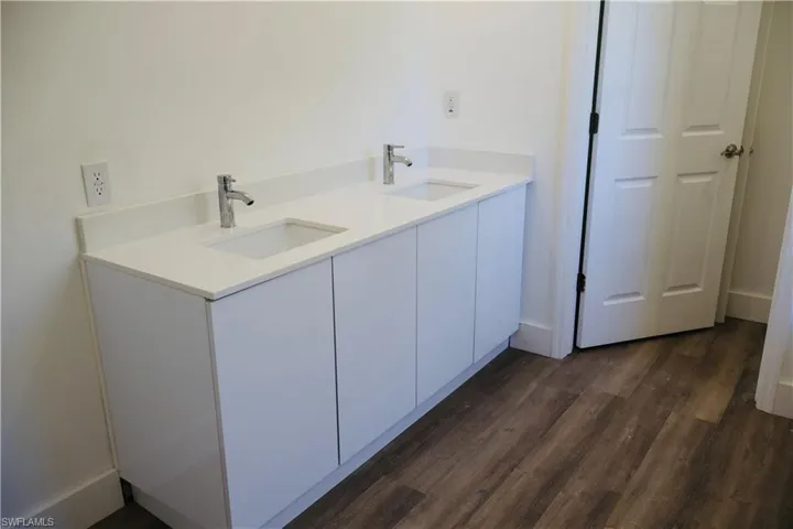 Full bath with double vanity and dark wood finished floors