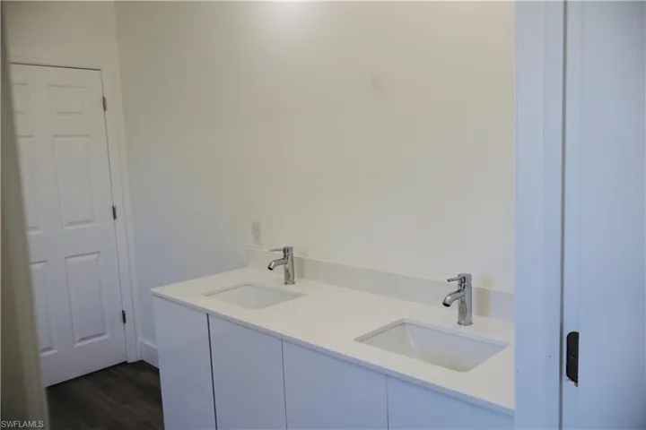 Full bathroom featuring double vanity and dark wood-style flooring
