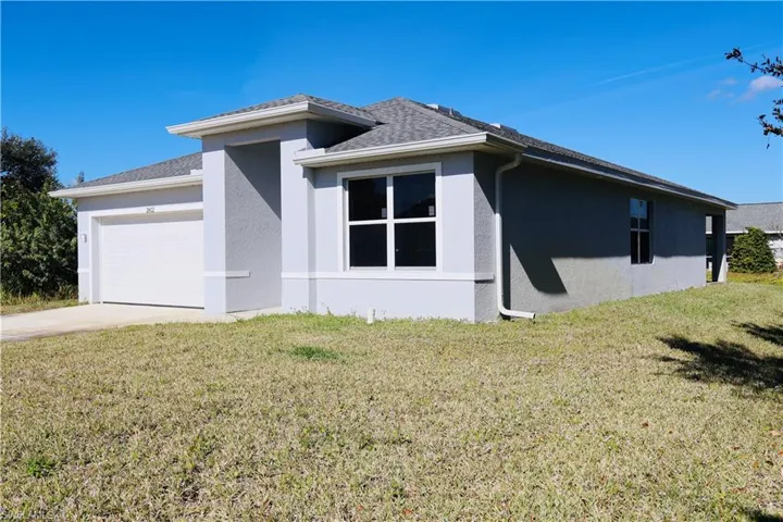 View of side of home with a lawn, stucco siding, and driveway