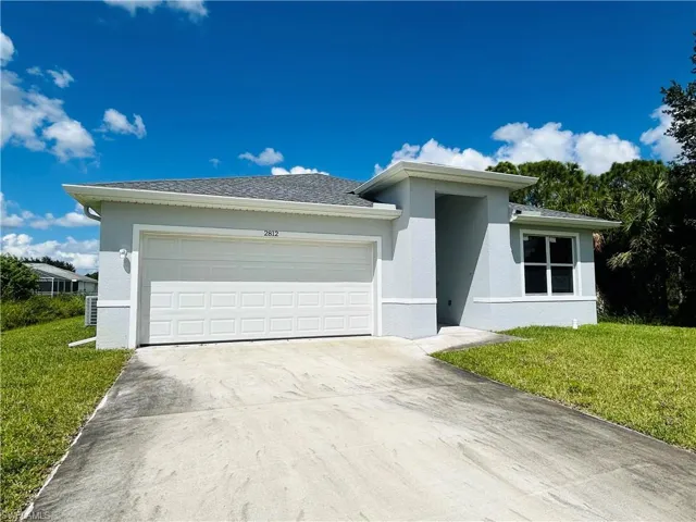 View of front of property featuring concrete driveway, stucco siding, a front yard, and an attached garage