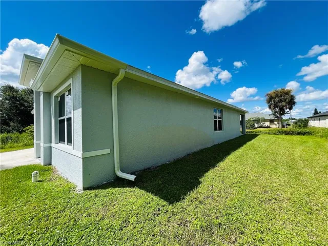 View of property exterior with a lawn and stucco siding