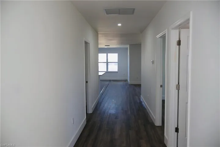 Hallway with dark wood finished floors and recessed lighting