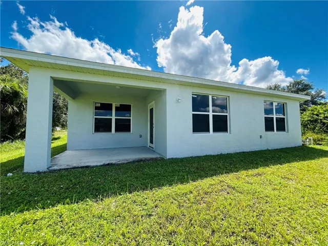 Back of house with stucco siding, a yard, and a patio area