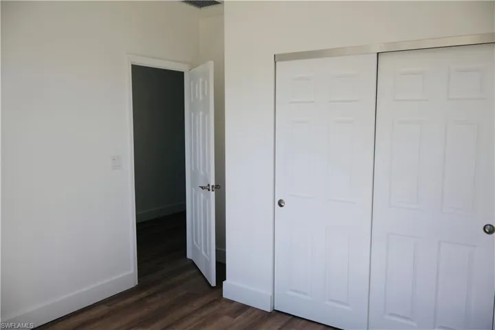 Unfurnished bedroom with dark wood-style floors and a closet