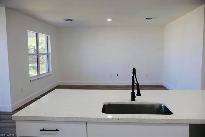 Kitchen featuring dark wood-type flooring, light stone countertops, white cabinetry, and recessed lighting