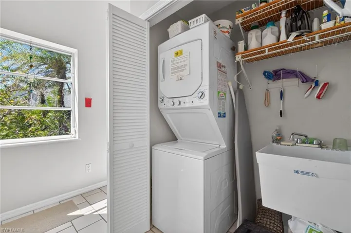 Laundry area with stacked washer and clothes dryer and light tile patterned floors