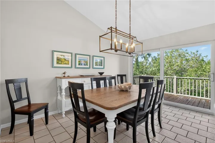 Dining space featuring vaulted ceiling, suspended lighting, and light tile patterned floors