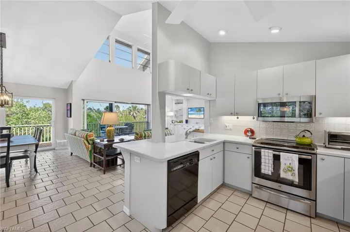 Kitchen featuring tasteful backsplash, stainless steel appliances, light countertops, a peninsula, and lofted ceiling