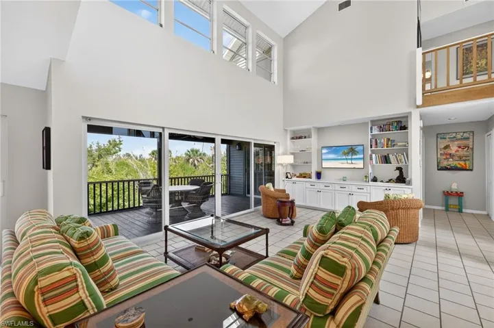 Living area featuring plenty of natural light, built in features, light tile patterned floors, and lofted ceiling