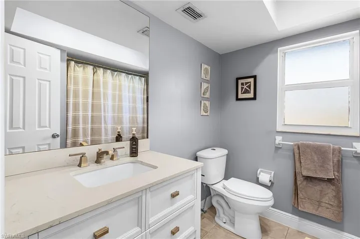 Full guest bathroom with a shower with curtain, vanity, and light tile patterned floors