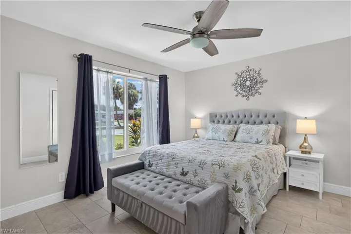 Spacious bedroom with ceiling fan including furnishings and large impact window for plenty of natural sunlight