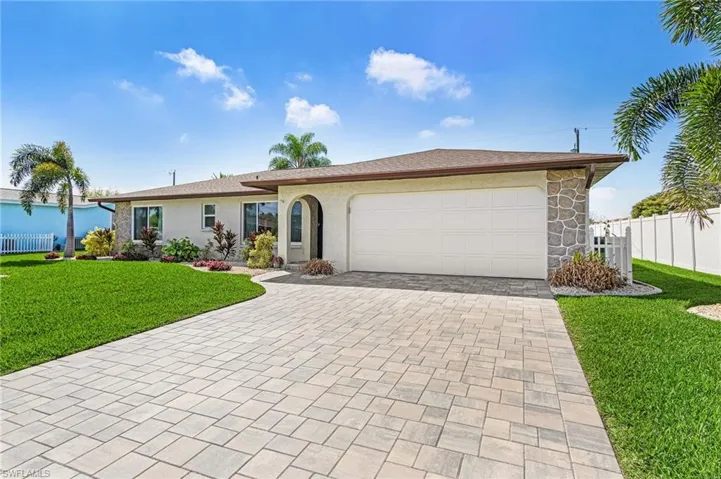 Ranch-style home with driveway, a garage, stucco siding, and stone siding