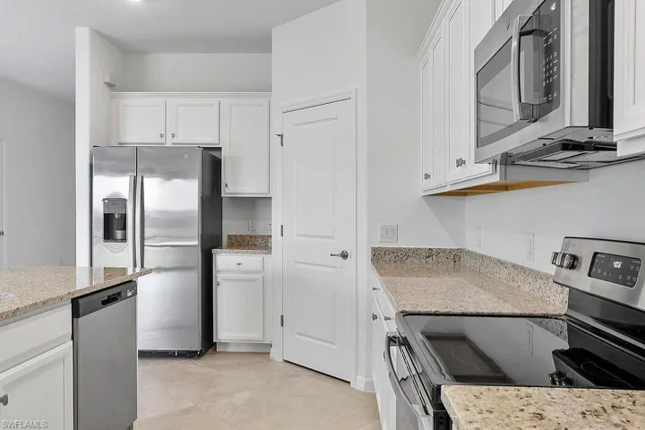 Kitchen featuring stainless steel appliances, white cabinetry, granite countertops, and tile flooring