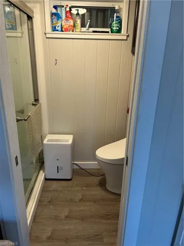 Full bath with a shower stall, toilet, and wood finished floors