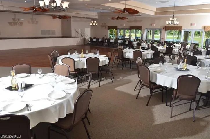 Carpeted dining room featuring a chandelier and a ceiling fan