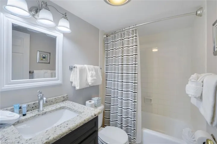 Full bathroom with vanity, shower / bathtub combination with curtain, and toilet