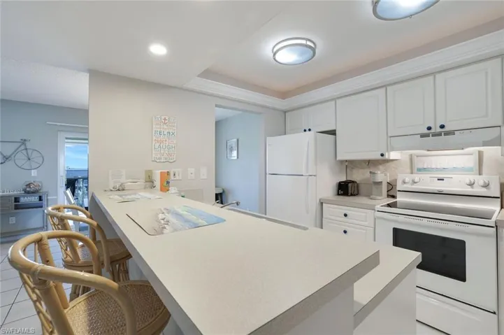 Kitchen featuring white cabinetry, white appliances, kitchen peninsula, and decorative backsplash
