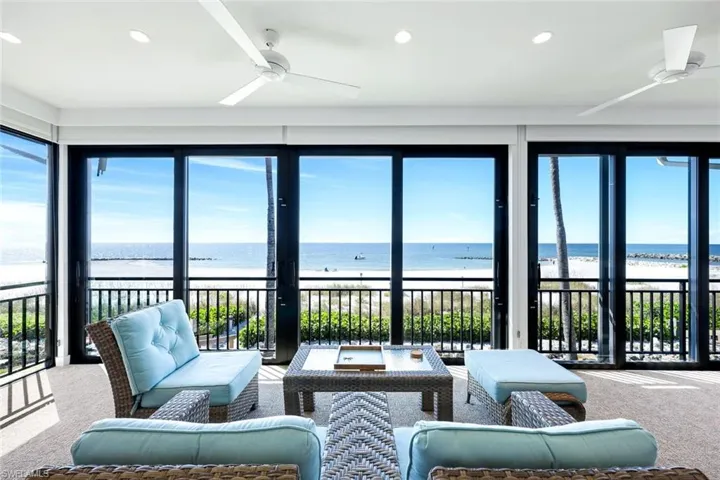 Sunroom featuring carpet, view of water and beach, and recessed lighting