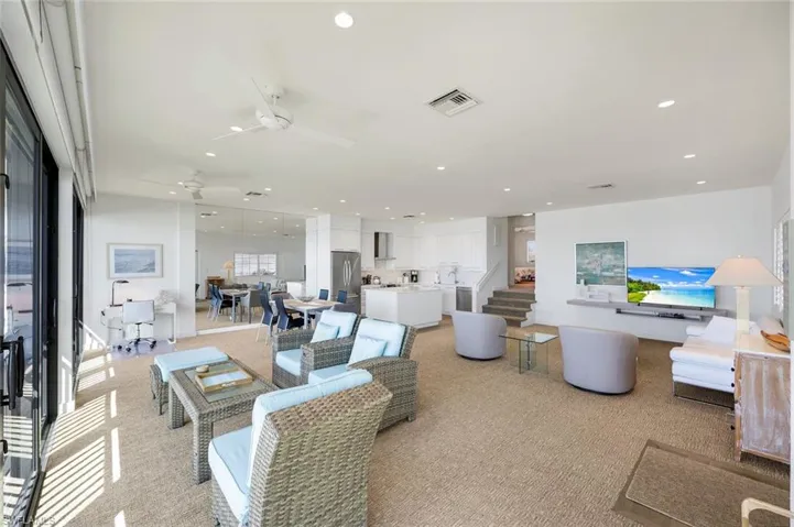 Living room featuring stairs, ceiling fan, recessed lighting, and light colored carpet