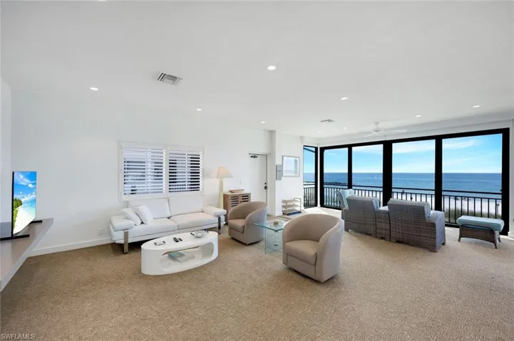 Living room featuring light carpet, a water view, recessed lighting, and ceiling fan