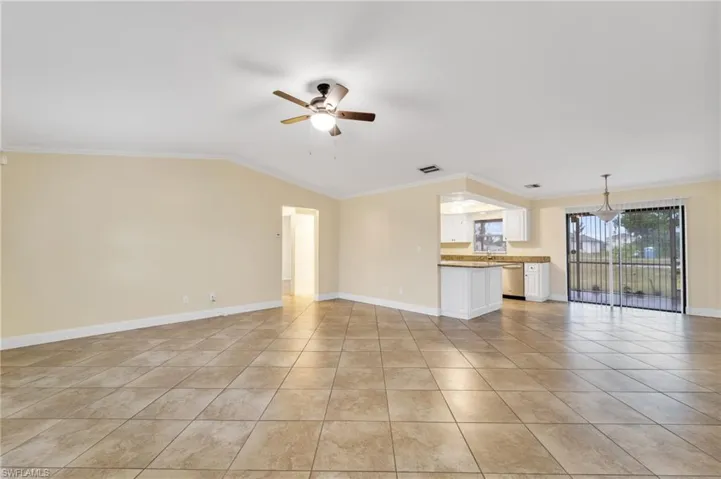 Unfurnished living room featuring crown molding, a ceiling fan, lofted ceiling, and light tile patterned floors