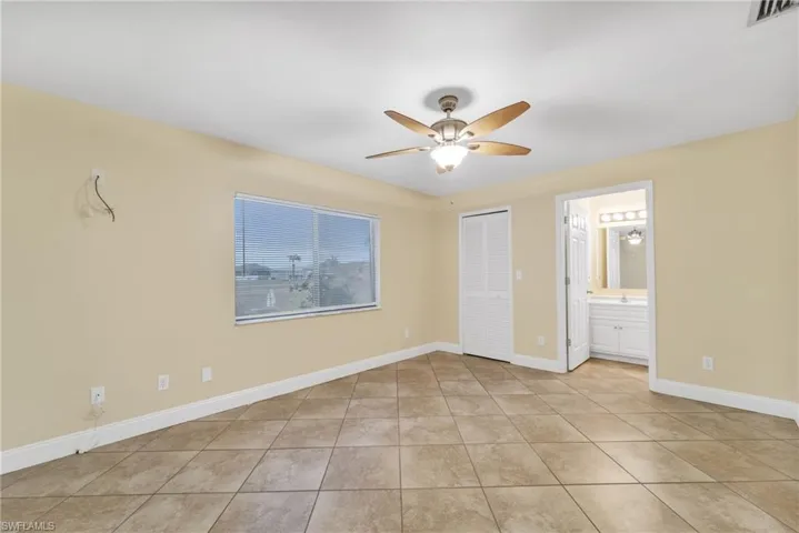 Unfurnished bedroom featuring a closet, a ceiling fan, and light tile patterned floors