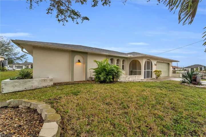 View of front of house featuring stucco siding, a front yard, an attached garage, and driveway