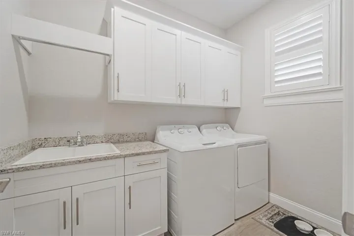 Clothes washing area featuring sink, separate washer and dryer, cabinets, and light hardwood / wood-style flooring