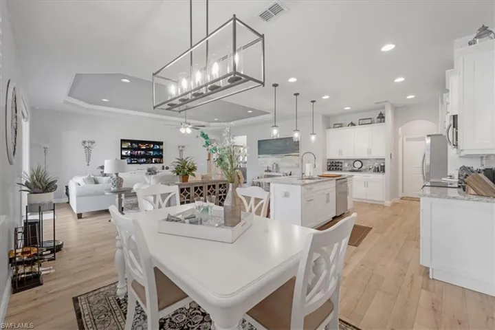 Dining space with a raised ceiling, ceiling fan, and light hardwood / wood-style floors