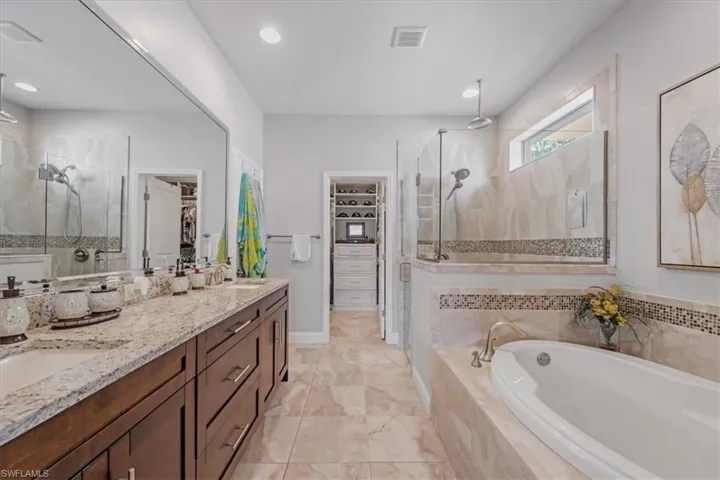 Bathroom with tile flooring, double sink, oversized vanity, and plus walk in shower
