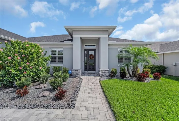 View of exterior entry featuring french doors and a lawn