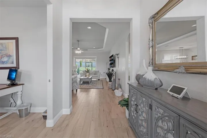 Hall with a tray ceiling, light hardwood / wood-style floors, and a notable chandelier