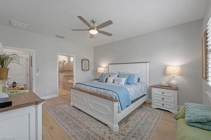 Bedroom featuring light hardwood / wood-style floors, ensuite bathroom, and ceiling fan