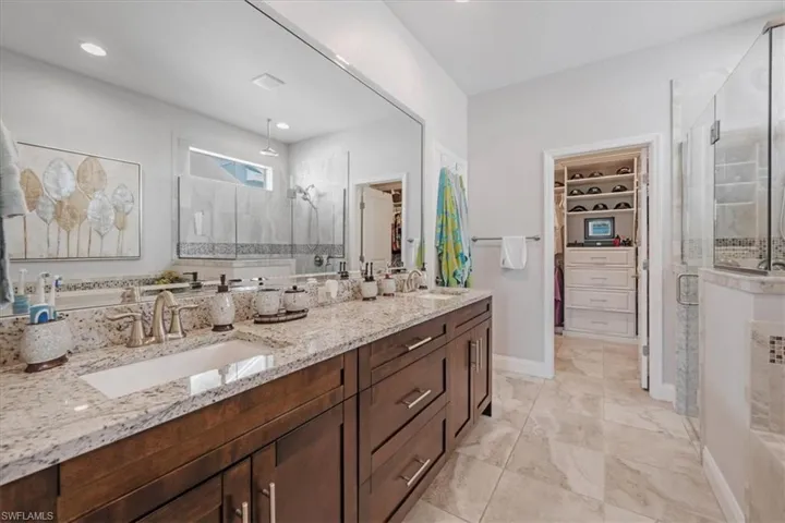 Bathroom featuring tile floors, dual bowl vanity, and a shower with shower door