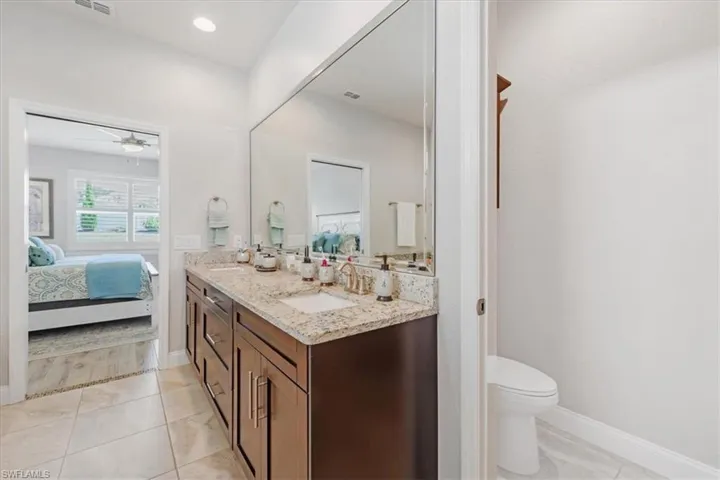 Bathroom with ceiling fan, dual vanity, toilet, and tile floors