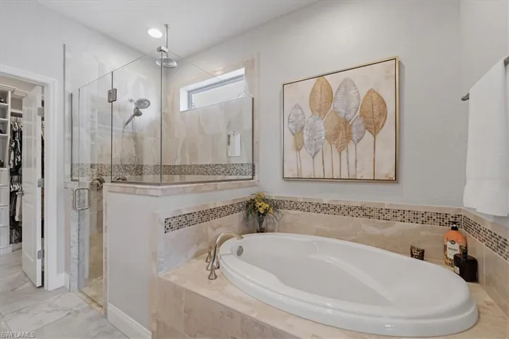 Bathroom with shower with separate bathtub and tile flooring