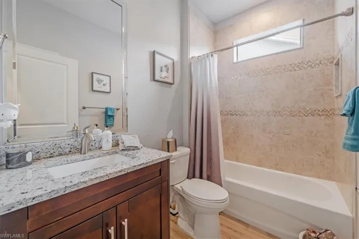 Full bathroom featuring wood-type flooring, shower / bath combo with shower curtain, vanity, and toilet
