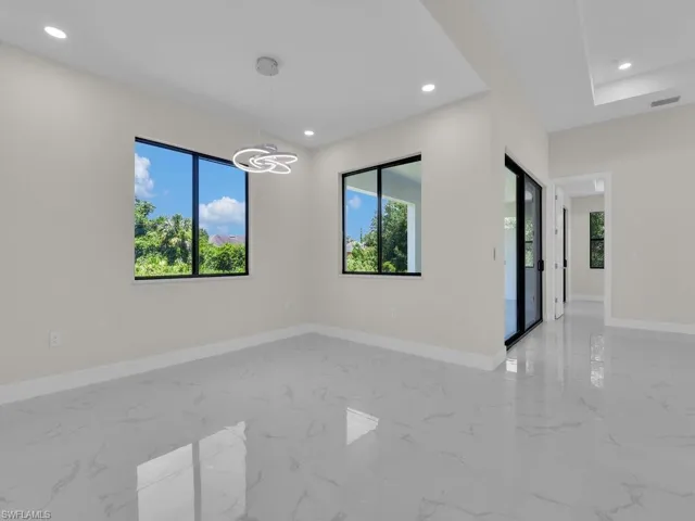 Unfurnished room with plenty of natural light, light marble finish floors, recessed lighting, and a chandelier
