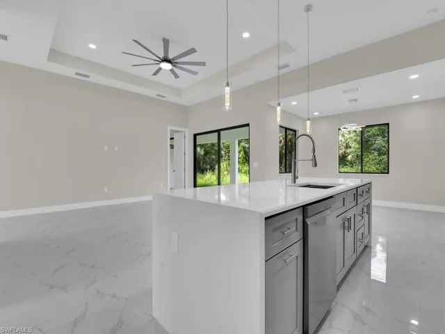 Kitchen featuring light marble finish floors, dishwasher, open floor plan, a raised ceiling, and recessed lighting
