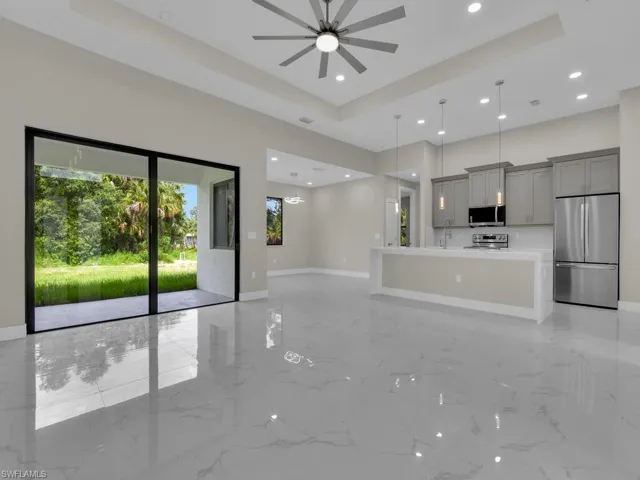 Unfurnished living room with a ceiling fan, light marble finish flooring, recessed lighting, and a raised ceiling