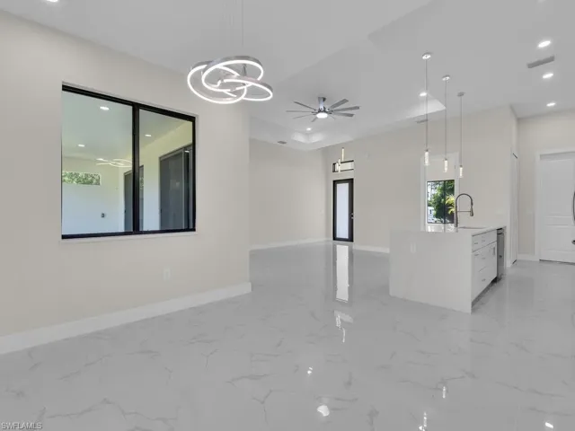 Unfurnished living room with ceiling fan, a chandelier, recessed lighting, and light marble finish flooring