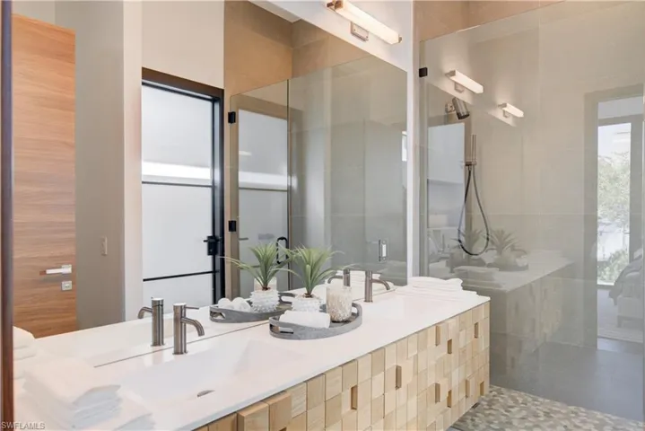 Bathroom featuring a tile shower, tile patterned flooring, and vanity