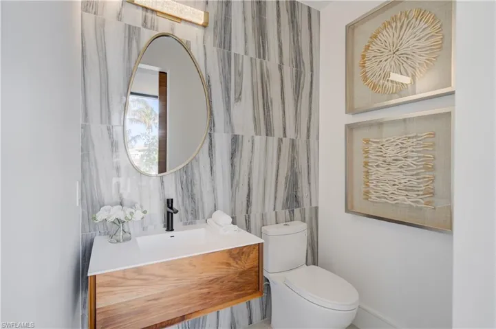 Bathroom featuring vanity, tile walls, and toilet